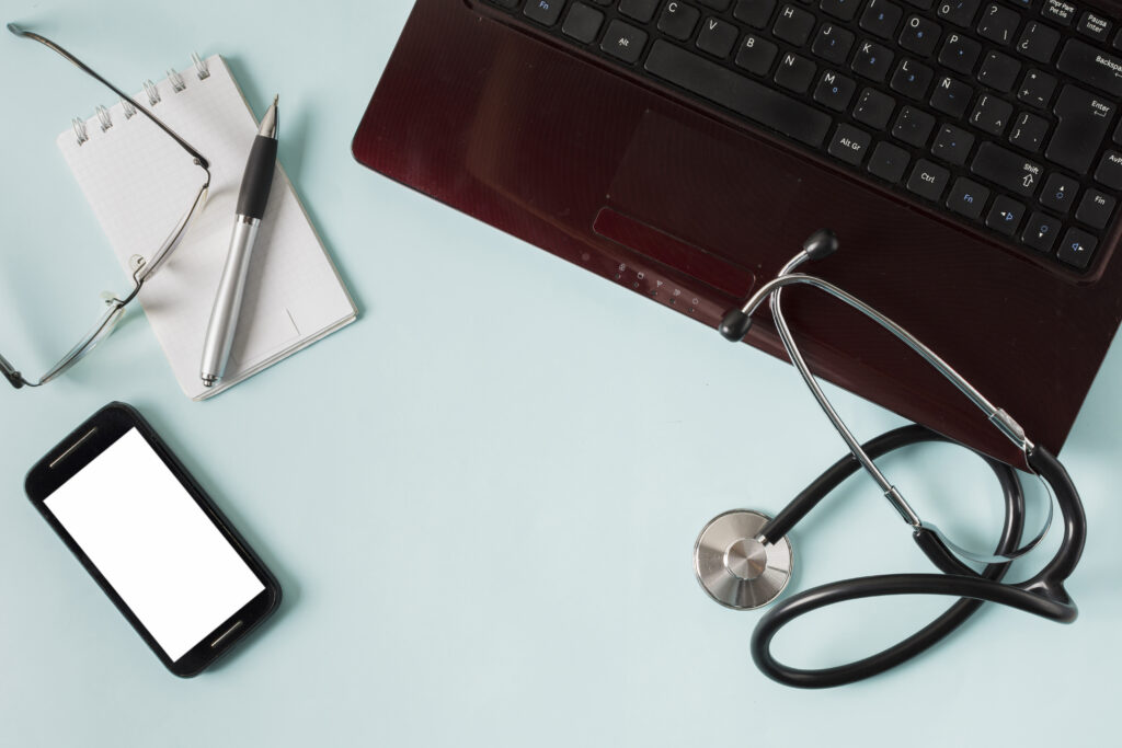Stethoscope, notebook and laptop on a light blue desk